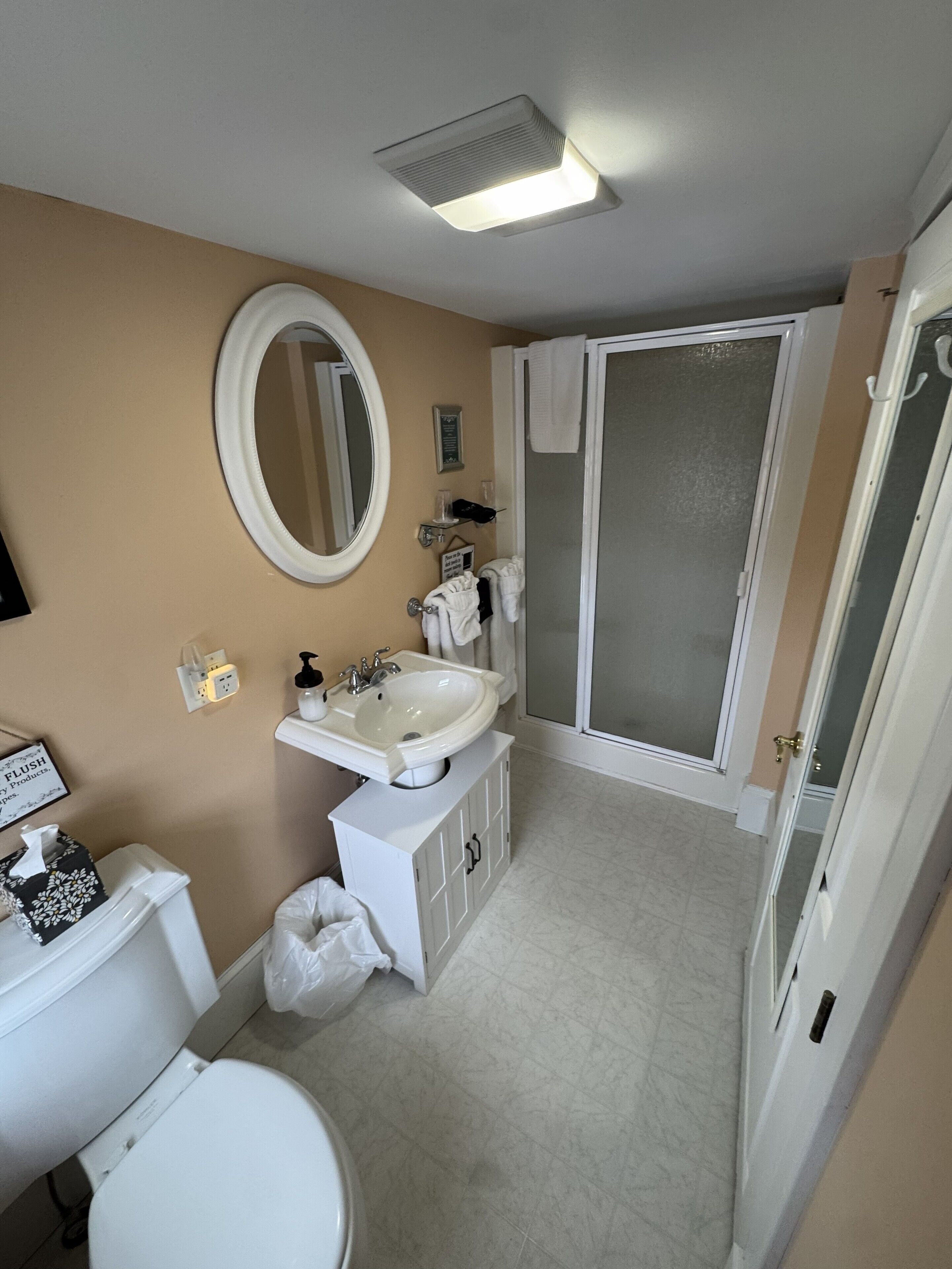 Een badkamer met toilet, wastafel, spiegel en douche.