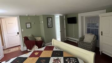 A bedroom with a large bed, a chair, a television, and a wardrobe.