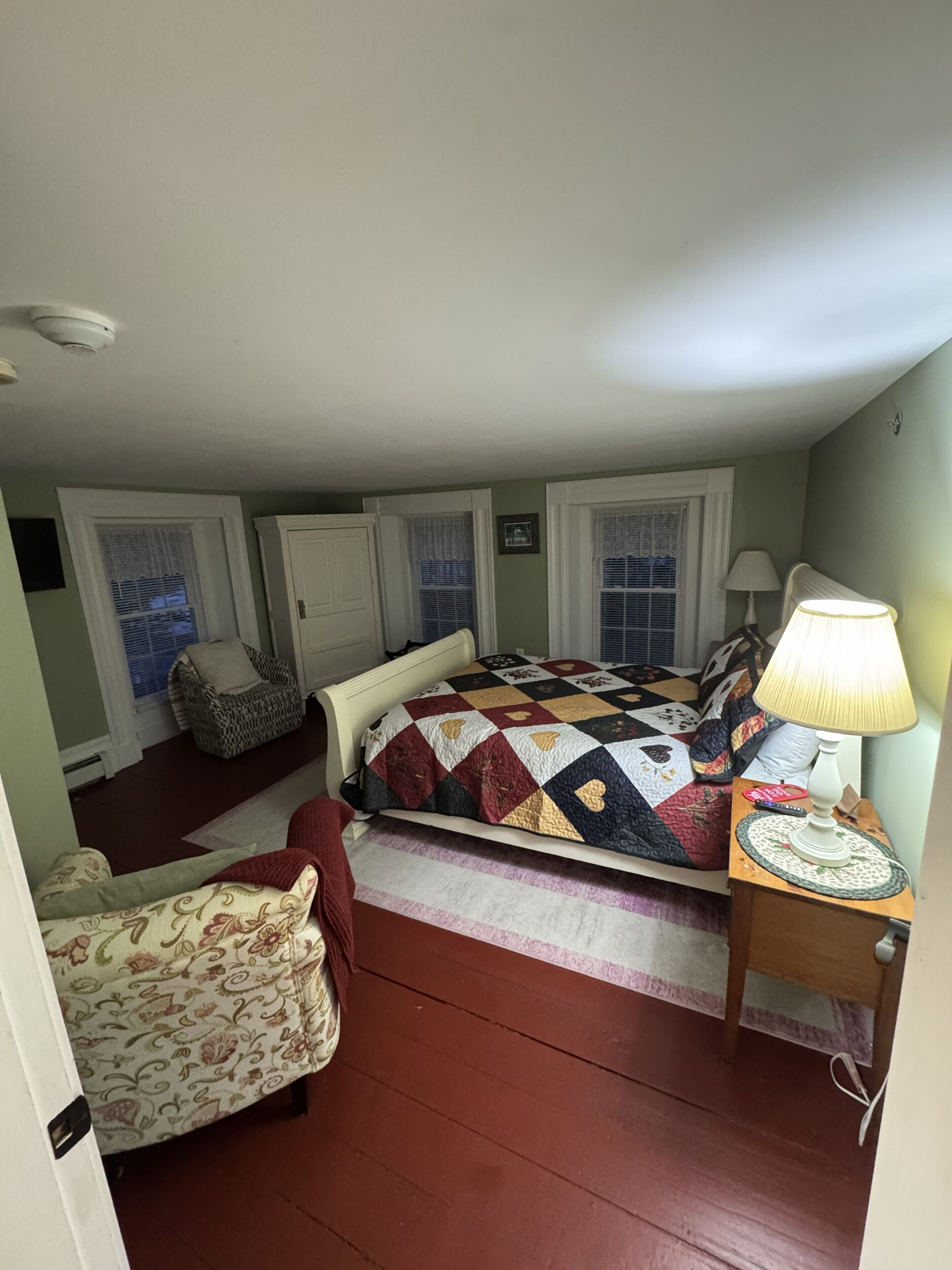 Une chambre à coucher avec un lit, une chaise, une lampe et une fenêtre.