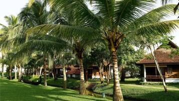 Un complexe hôtelier tropical doté de palmiers, d’un petit plan d’eau et de bâtiments de style traditionnel.