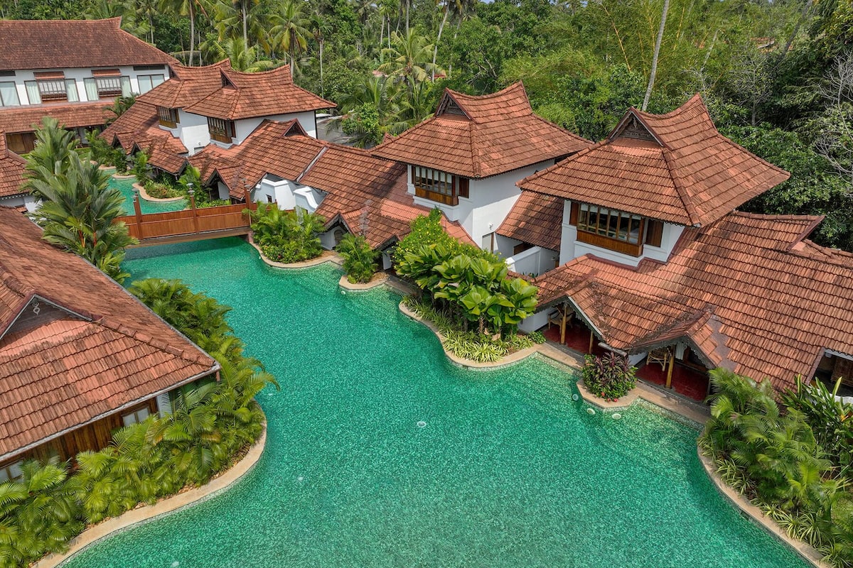 Ein Resort mit mehreren bungalowsartigen Gebäuden, einem zentral gelegenen Pool und üppiger tropischer Vegetation.