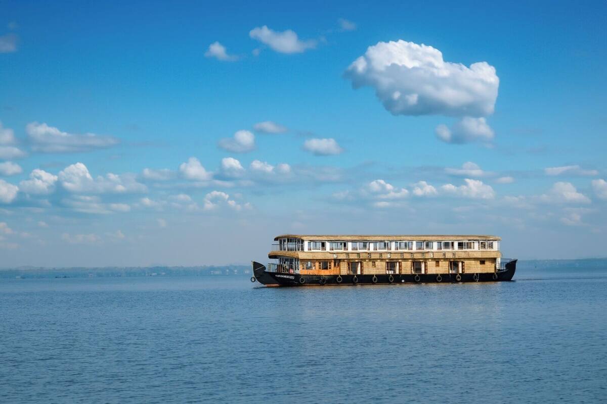 Ein Flussdampfer mit mehreren Decks und einem Reisstrohdach, der auf ruhigem Wasser schwimmt.