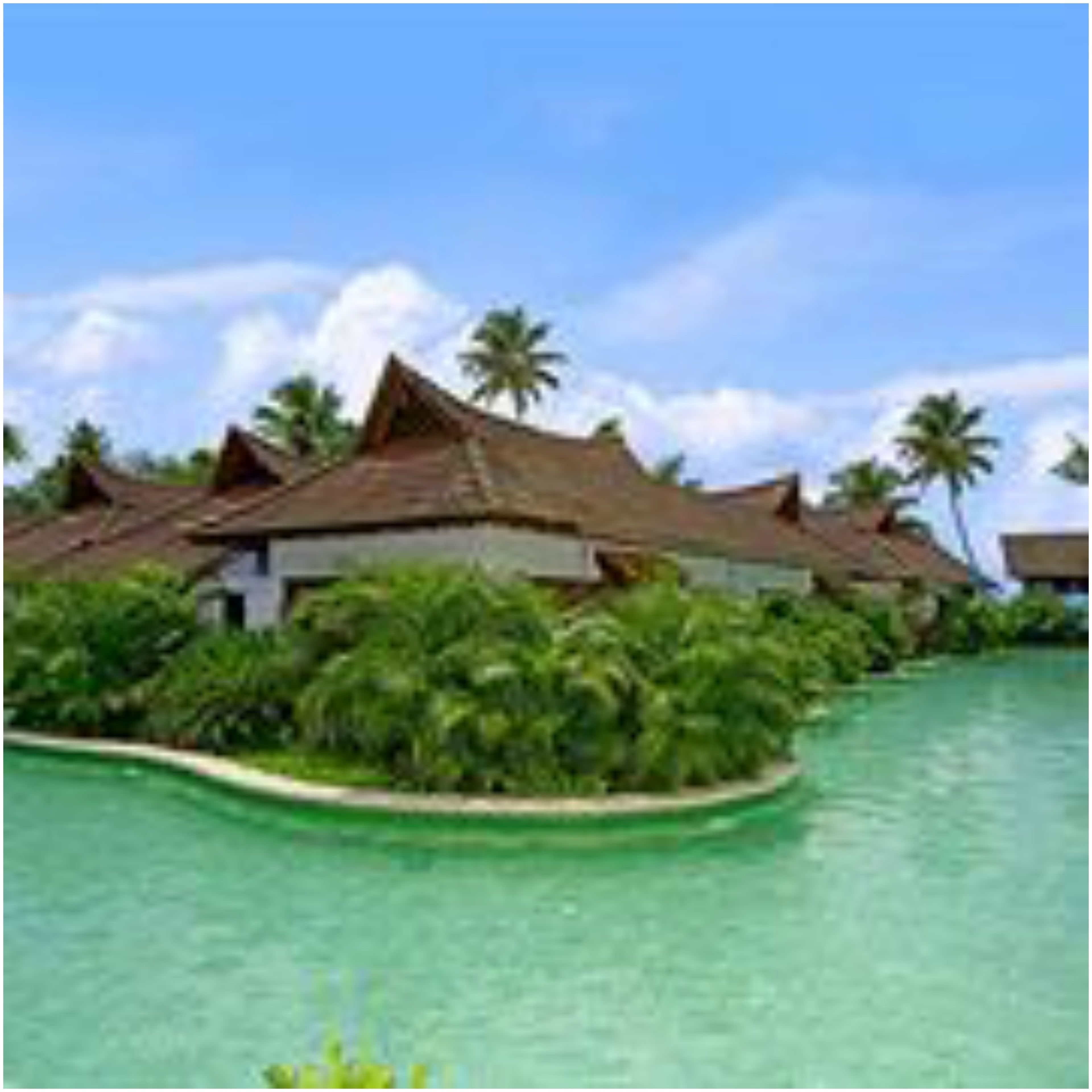 A resort with multiple bungalow-style buildings, a swimming pool, and palm trees.