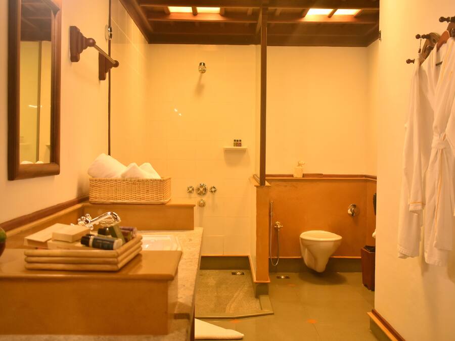 Un baño con bañera, inodoro y lavabo. Hay toallas colgadas en la pared y una repisa con artículos de aseo.