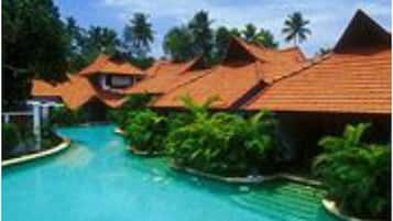 Un resort con varias cabañas sobre el agua, una piscina y exuberante vegetación tropical.
