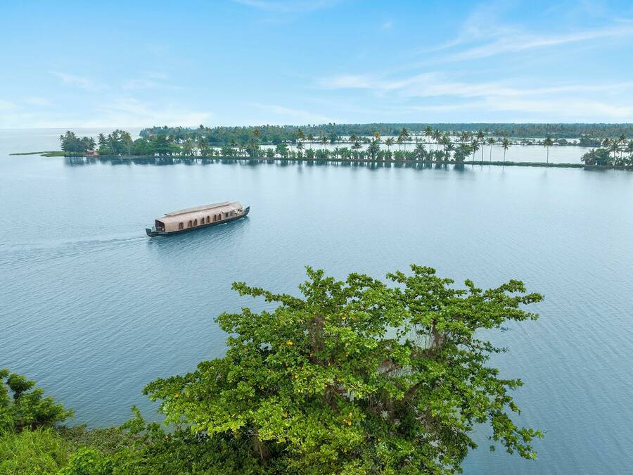 Un barco de paseo recorre un río tranquilo, con orillas boscosas y árboles a la distancia.