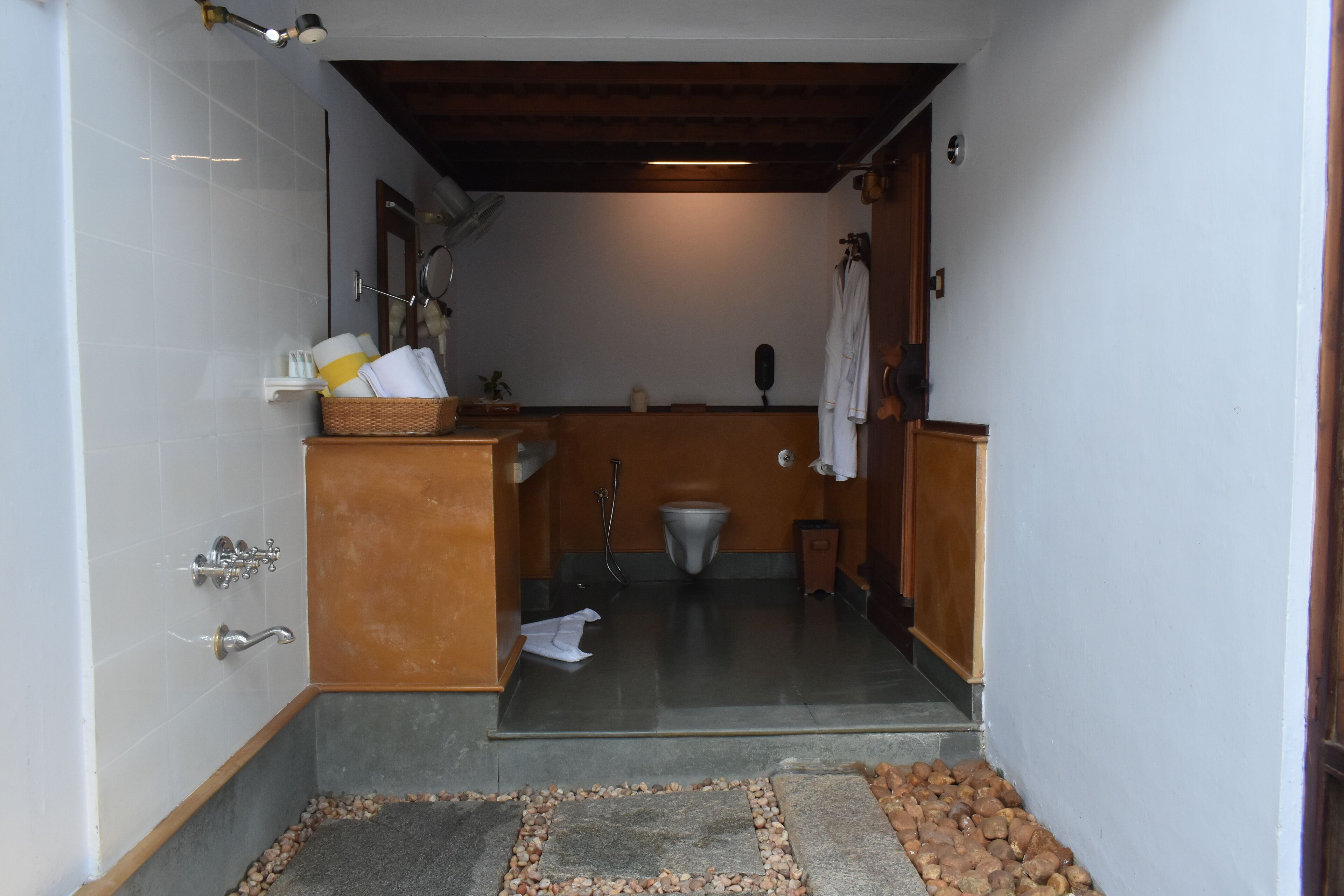 A narrow bathroom with a shower, toilet, and a small sink area.