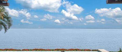 A pool with a clear view of the sea and a tropical setting.