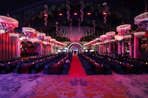A banquet hall with long tables, red carpet, and hanging floral decorations. - Mapple Emerald (New Delhi)