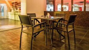 An outdoor dining area with a table and chairs, a tiled floor, and a brick wall. - Hotel Grand Godwin near the New Delhi railway station & Connaught Place. (New Delhi)