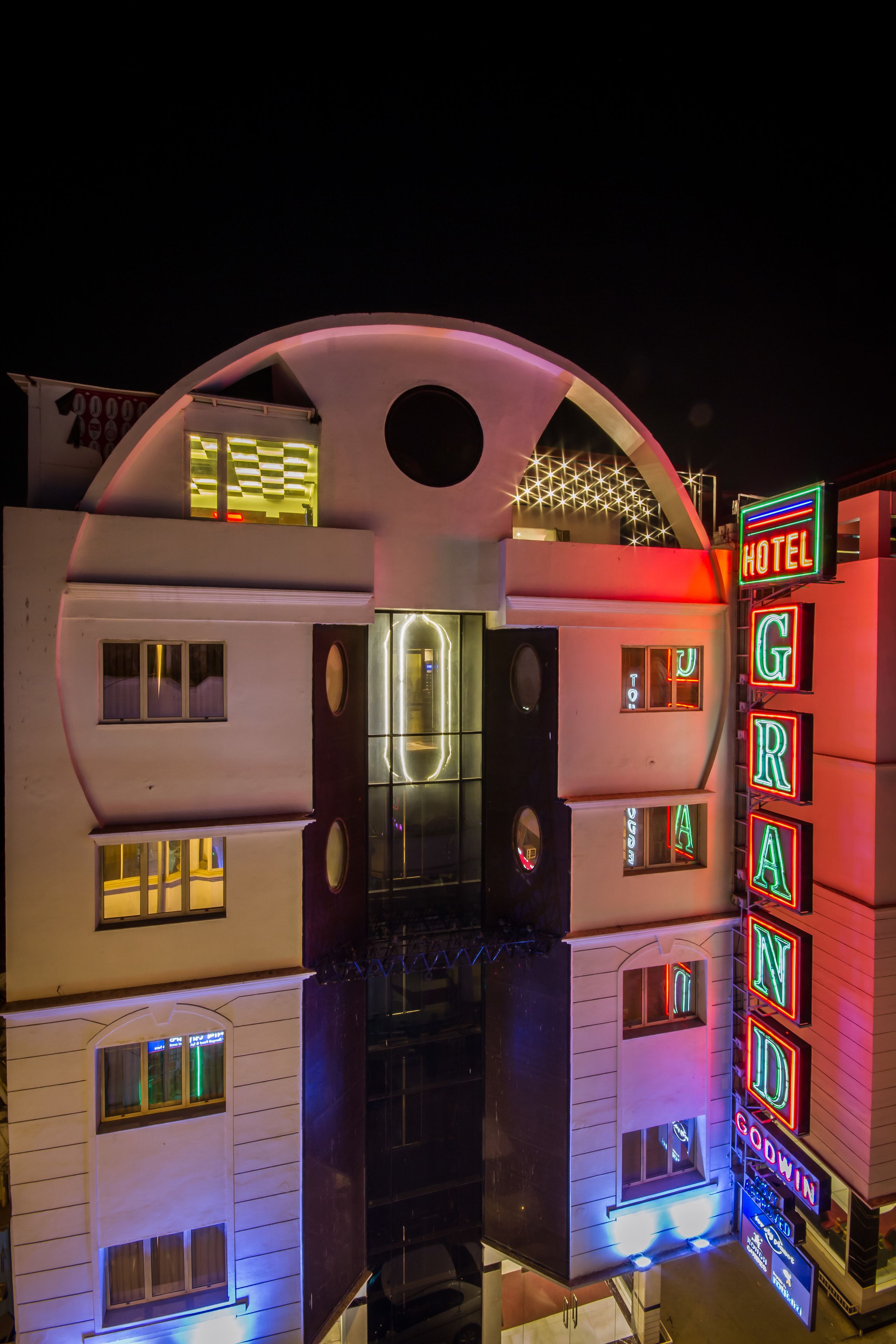 Un hotel con una entrada de arco distintivo, señalización de neón y múltiples ventanas.