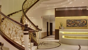 A grand staircase with ornate railings and a marble floor with a sun design. - Hotel Grand Godwin near the New Delhi railway station & Connaught Place. (New Delhi)