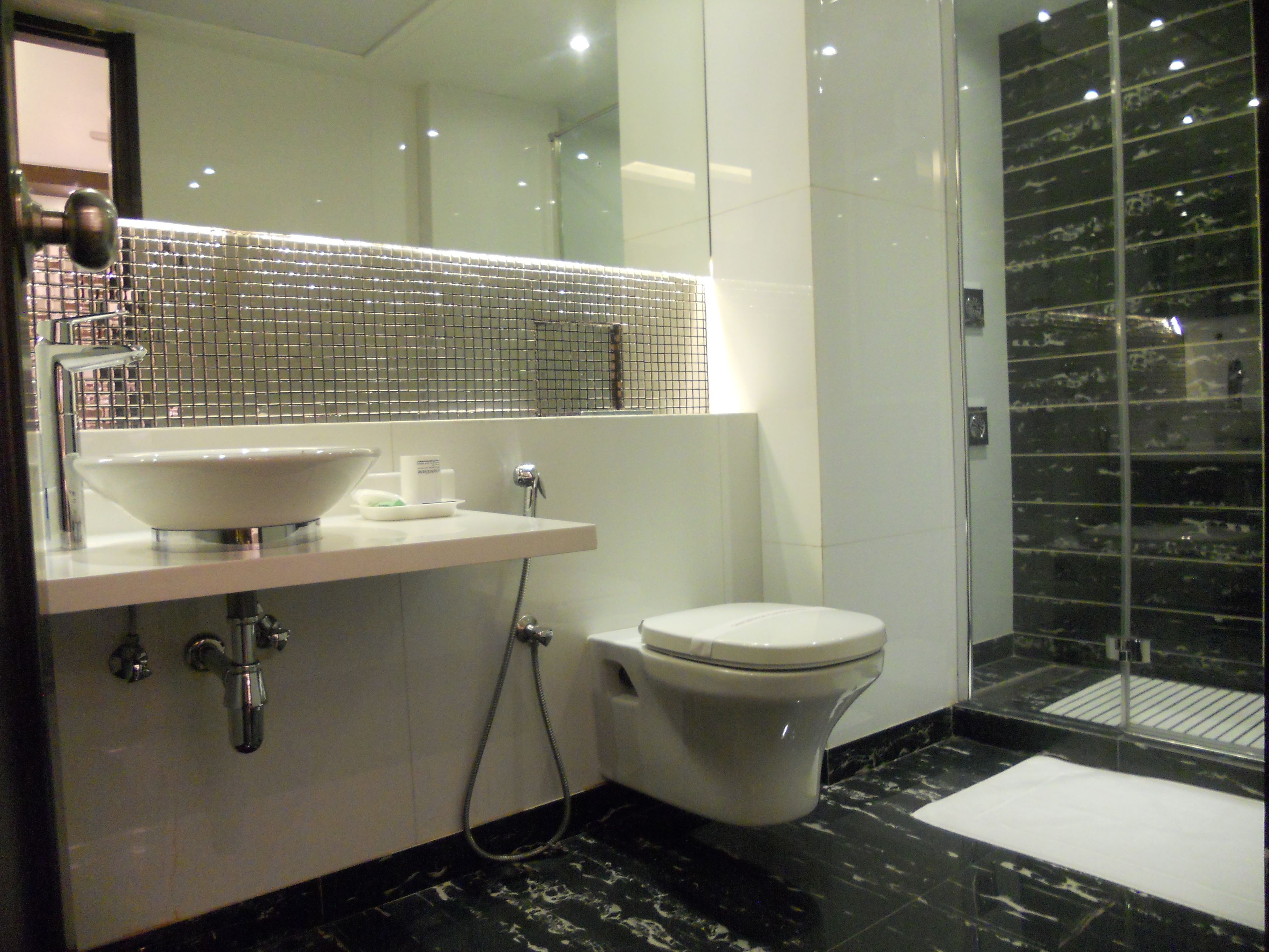 Un baño moderno con lavamanos, espejo y inodoro blancos.