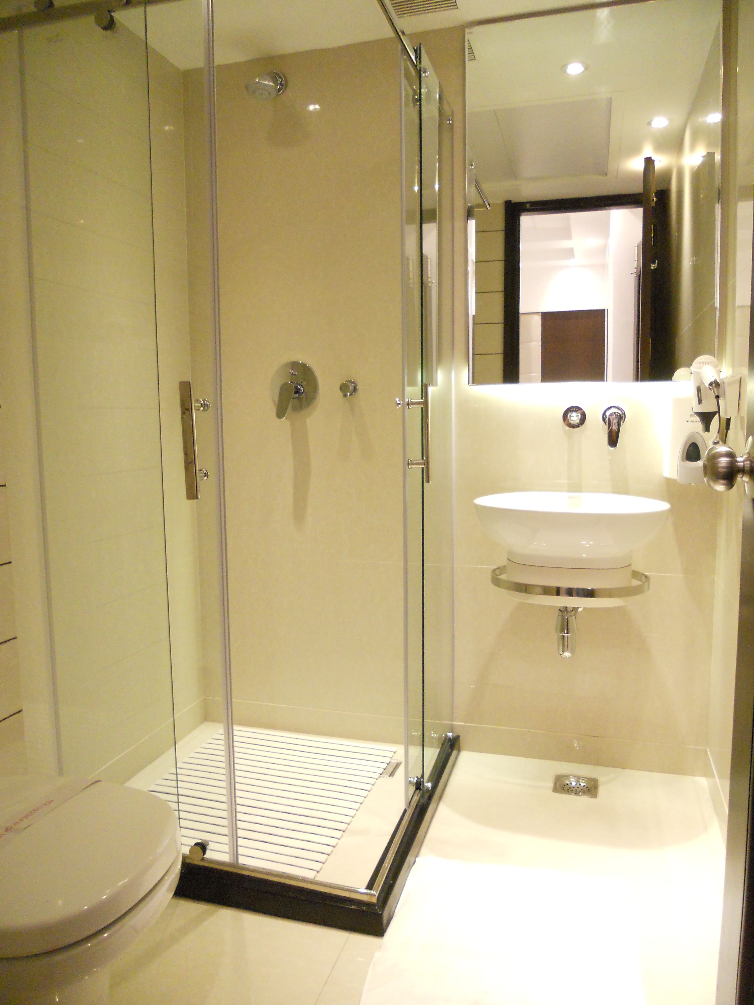 A modern bathroom with a glass-enclosed shower, a white sink, and a toilet.
