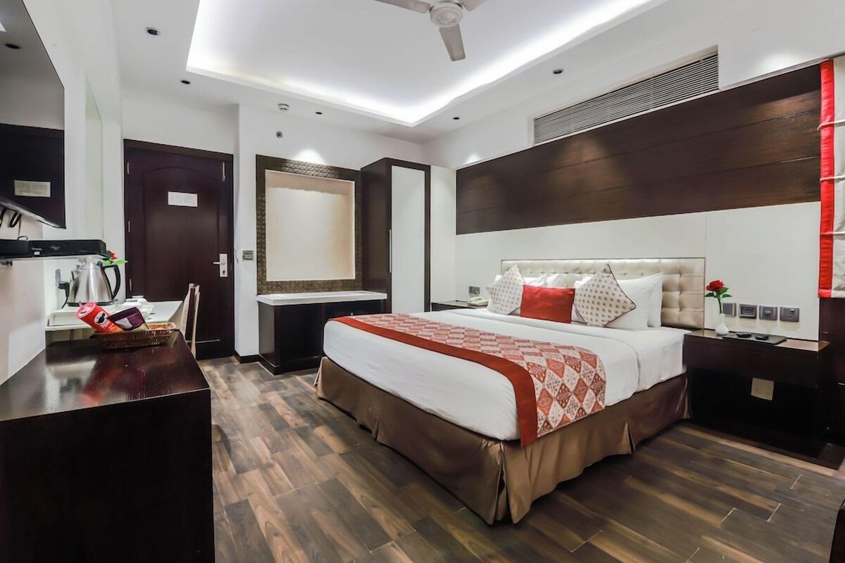 Une chambre d’hôtel moderne équipée d’un grand lit, d’un bureau, d’un miroir et d’un ventilateur de plafond.