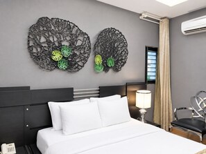 Ein Hotelzimmer mit Bett, Nachttisch, Lampe, Sessel und zwei Wandbildern.