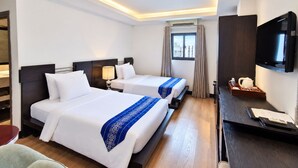 A hotel room with two beds, a desk with a television, and a window with curtains. - A&EM - The Petit Hotel (Ho Chi Minh City)