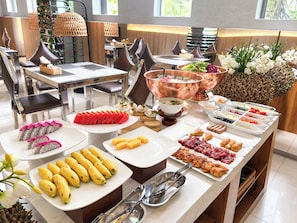 A buffet setup with various food items, a hot beverage station, and a decorative plant arrangement.