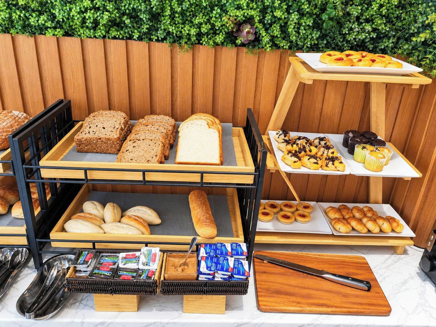 A breakfast buffet with various breads, pastries, and spreads.