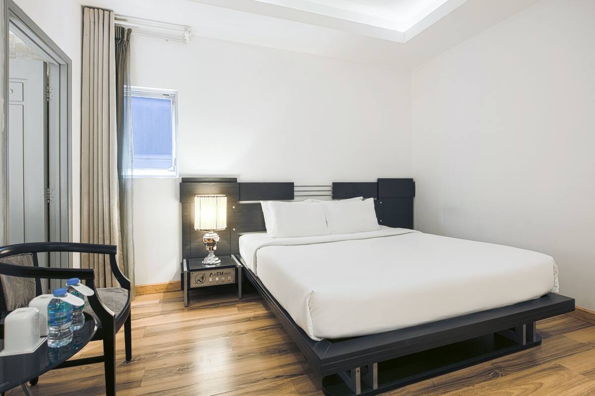 Ein modernes Hotelzimmer mit Bett, Nachttisch, Lampe und einem Sessel.