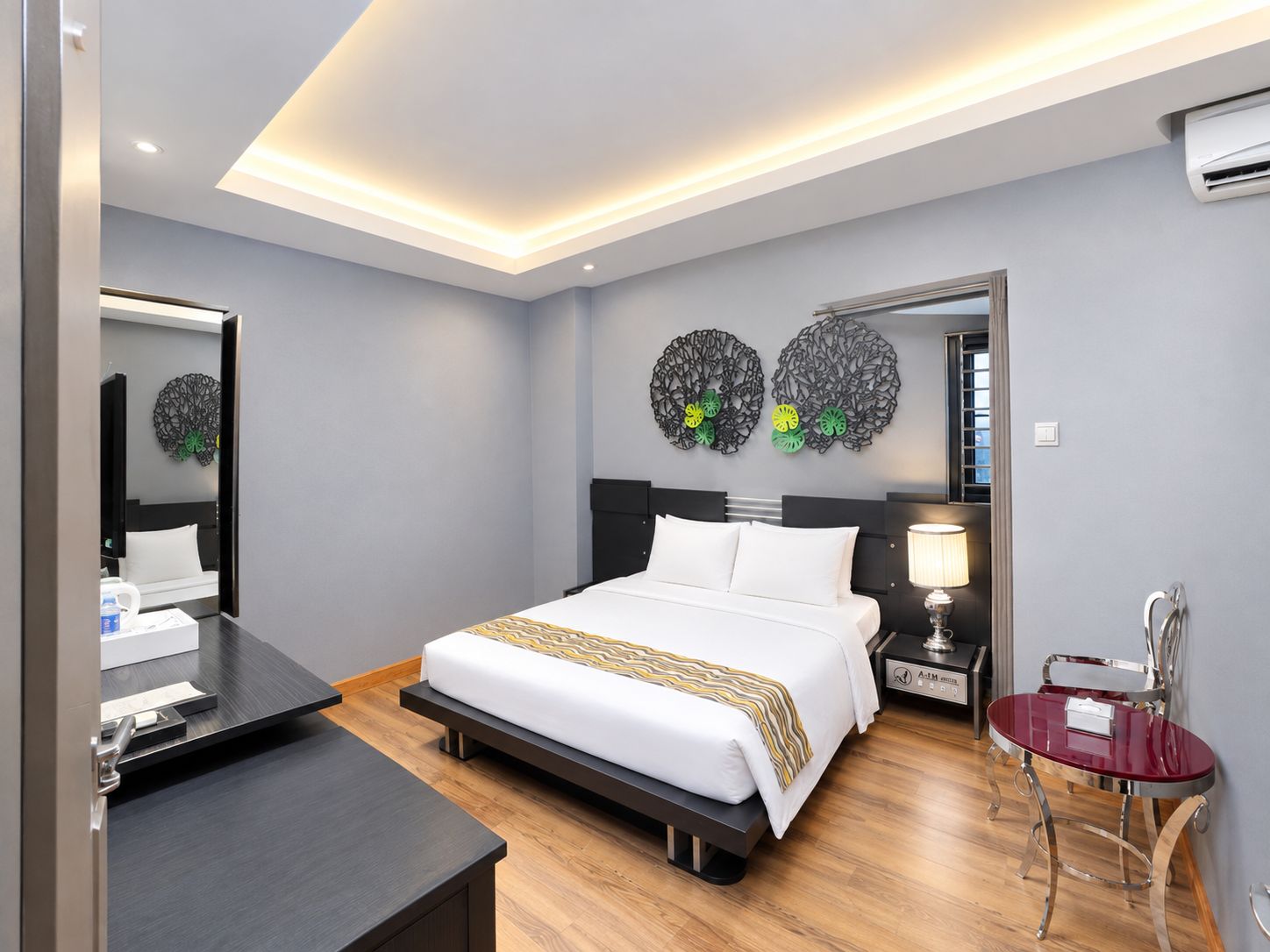 A modern hotel room with a bed, bedside table, lamp, and a mirror.