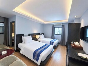 Ein Hotelzimmer mit zwei Betten, einem Schreibtisch, einem Fernseher und einem Fenster.