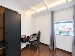 Ein Hotelzimmer mit Schreibtisch, Stuhl und Kleiderschrank.