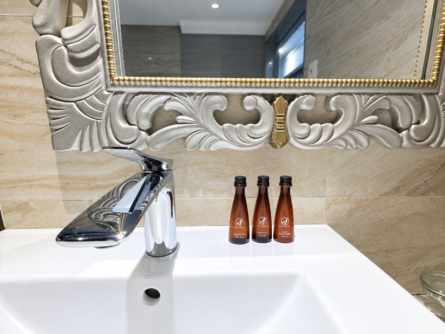 A bathroom with a white sink, a chrome faucet, and three brown bottles with labels.