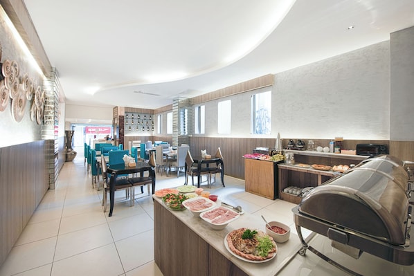 A modern dining area with a central island featuring a grill, surrounded by tables and chairs.