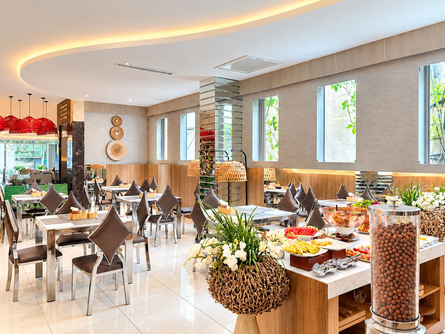 A modern dining area with multiple tables and chairs, a buffet with various food items, and large windows allowing natural light.