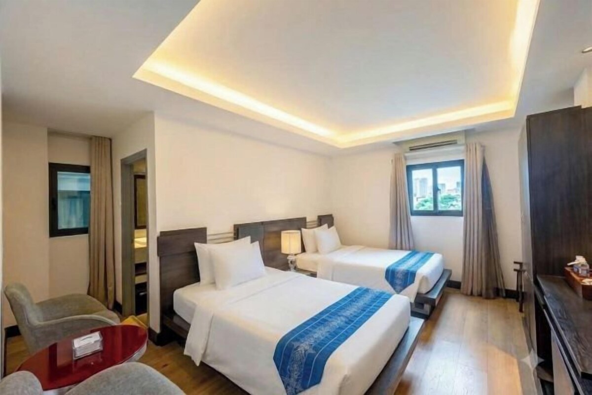 Une chambre d’hôtel avec deux lits, un bureau, une chaise et un téléviseur.