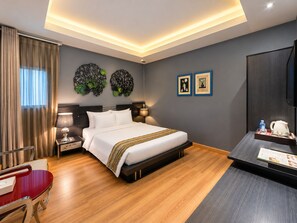 Une chambre d’hôtel avec un lit, des tables de chevet, un bureau et une chaise.