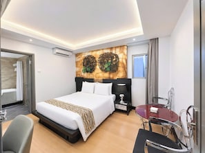 Ein modernes Hotelzimmer mit einem großen Bett, einem Nachttisch, einem Schreibtisch mit Stuhl und einem Fenster.