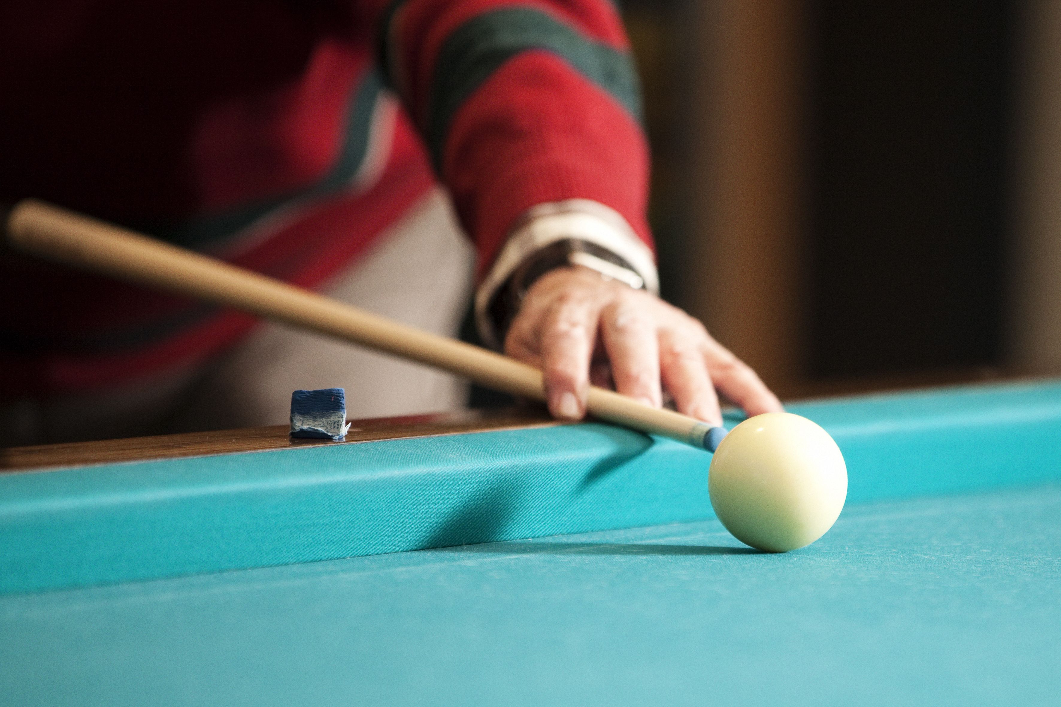 A close-up of a pool cue and a billiard ball on a pool table.