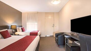 Een hotelkamer met twee bedden, een televisie, een bureau en een raam met gordijnen.
