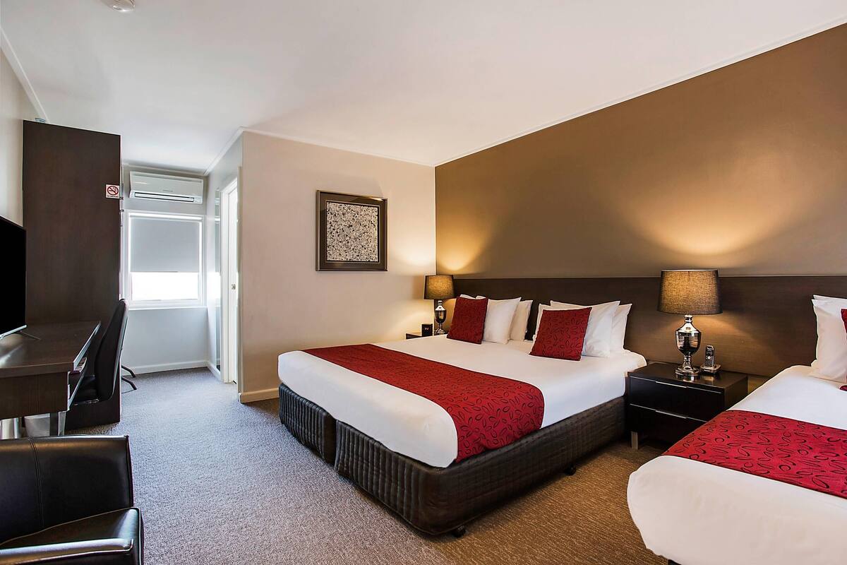 A hotel room with two beds, a desk, and a chair.