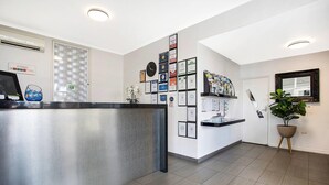 A reception area with a reception desk, framed certificates on the wall, a clock, and a potted plant. - Comfort Inn Western (Warrnambool)