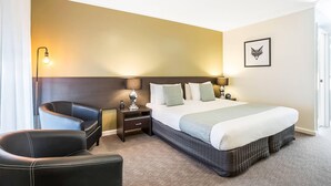 A hotel room with a bed, two bedside tables, a chair, and a lamp. - Comfort Inn Western (Warrnambool)