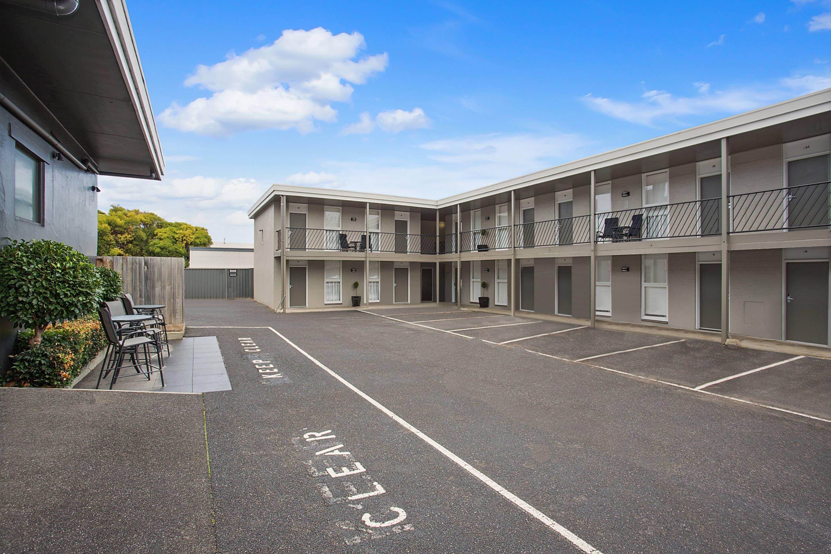 A multi-story motel with a parking area marked 'PARKING ONLY' and a clear sky.