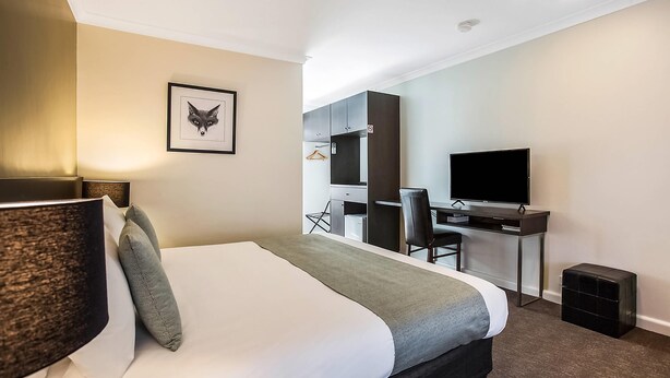 A hotel room with a bed, a desk, a chair, a television, and a framed picture on the wall. - Comfort Inn Western (Warrnambool)