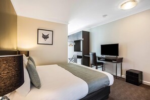 A hotel room with a bed, a desk, a chair, a television, and a framed picture on the wall. - Comfort Inn Western (Warrnambool)