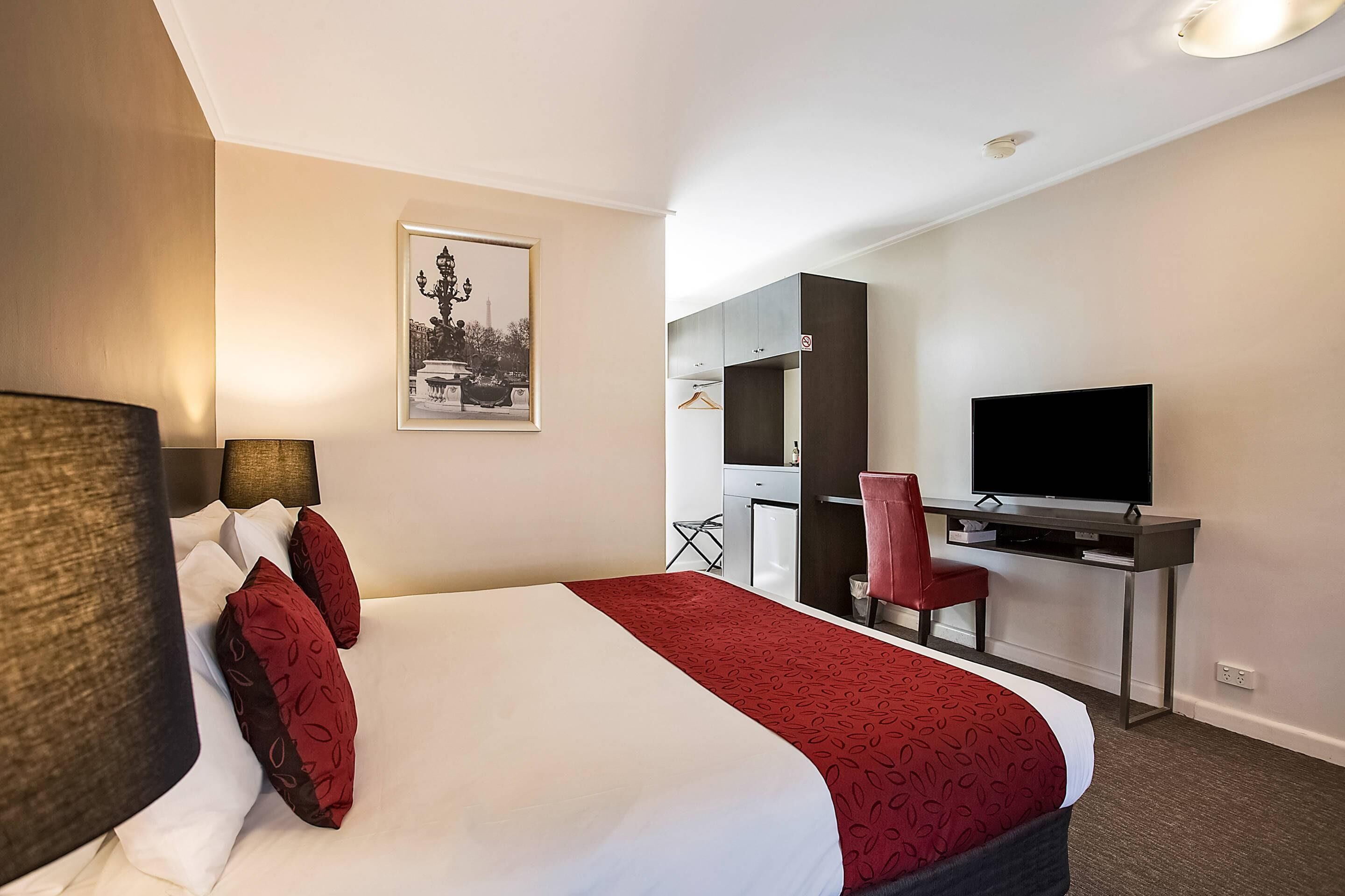A hotel room with a bed, a desk, a television, and a chair.