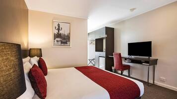 A hotel room with a bed, a desk, a television, and a chair.
