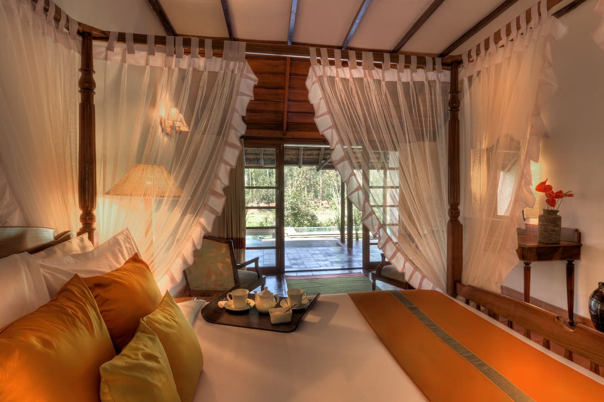 A room with a bed, a table with tea set, and a view of the outdoors.