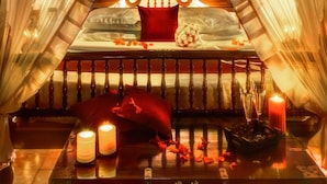 A cozy, intimate setting with a bed, candles, and a decorative headboard. - Evolve Back, Coorg (Virajpet)