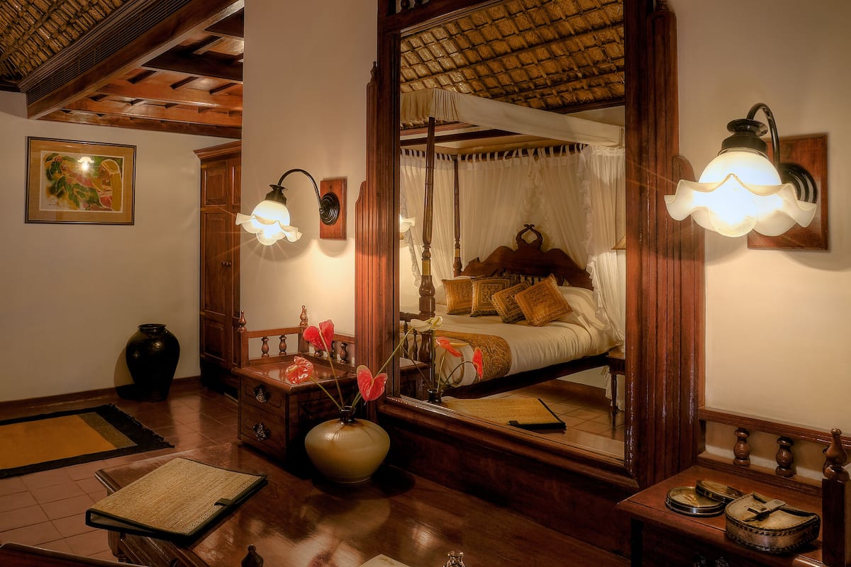 A traditional room with a large mirror, a bed with a canopy, and two wall-mounted lamps.