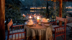 An outdoor dining area with tables set for two, candles, and a view of a mountainous landscape. - Evolve Back, Coorg (Virajpet)