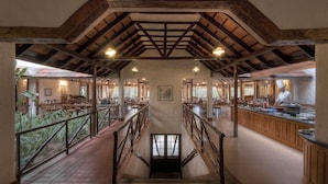 A spacious restaurant with high ceilings, wooden beams, and a central staircase. - Evolve Back, Coorg (Virajpet)
