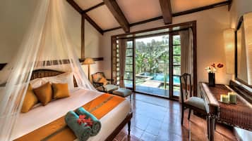 Un dormitorio con cama, una silla, una mesa con velas y vistas a una piscina y jardín.