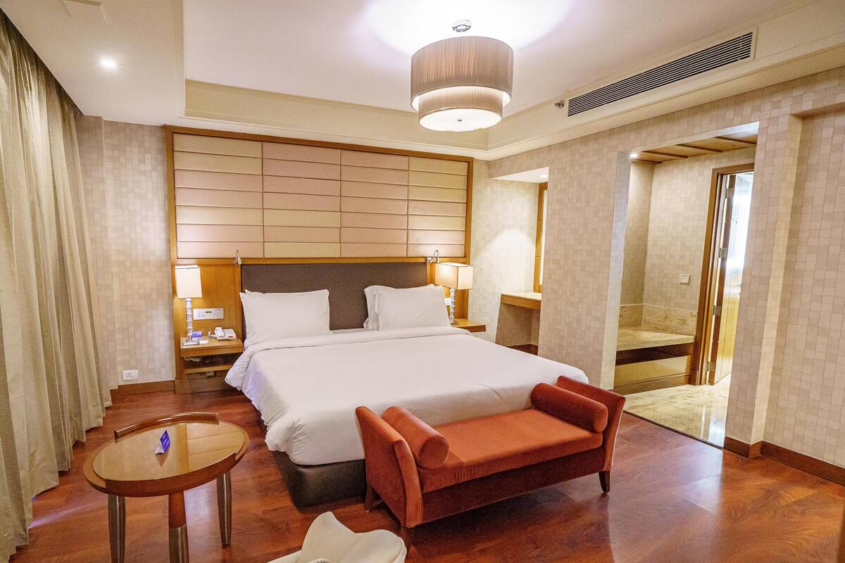 Una habitación de hotel con una cama grande, una mesita, un sofá y un espejo.